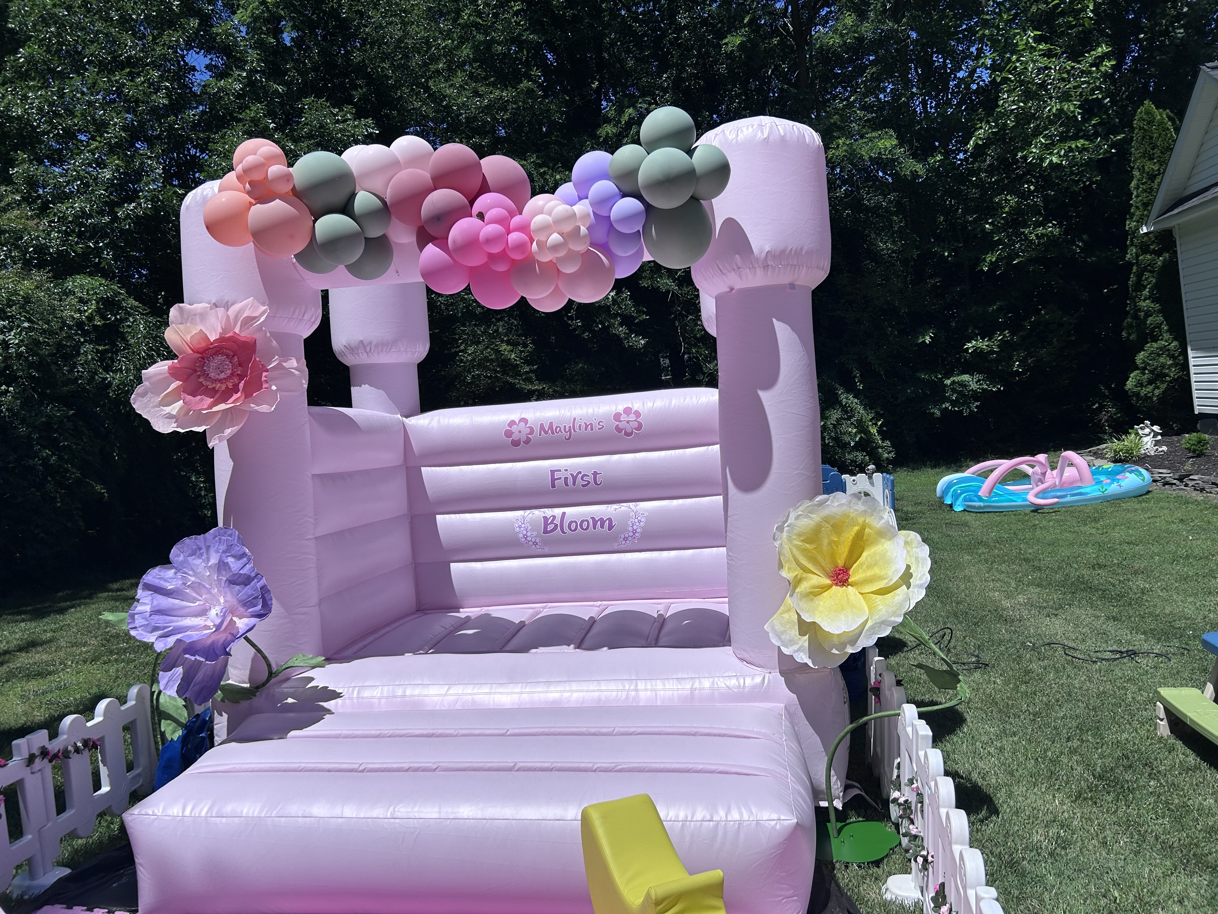 Pink mini bounce house with floral and balloon decor